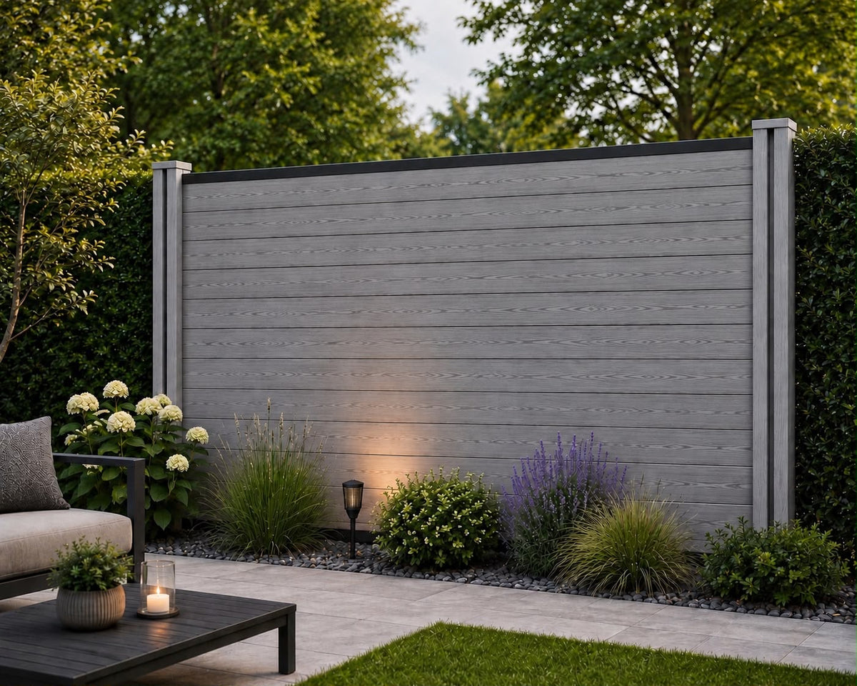 Anthracite composite fencing with horizontal grey wood-grain slats, matching posts and a black top rail, behind a planted garden border beside a patio.