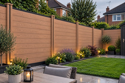 Composite Fencing Panel Set Dark Teak installed in a landscaped British back garden with outdoor dining area and garden border lighting at dusk